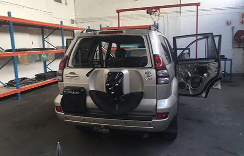 Toyota Land Cruiser Prado in a workshop bay with its rear passenger door open and the trim removed